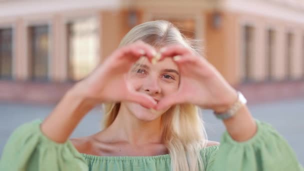 Glücklich Lächelnde Junge Hübsche Frau Zeigt Herzform Mit Fingern Draußen — Stockvideo