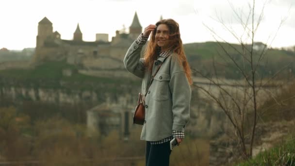 年轻美丽的女游客欣赏城堡城堡的奇景 微笑着 风吹着她的头发 — 图库视频影像