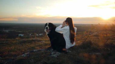 Bernese Dağı Köpeği. Komik şirin köpek kendini iyi hissediyor büyük kulaklıklarla müzik dinliyor ve kafasını sallıyor. Keyfine bak. Komik, eğlenceli evcil hayvanlar konsepti. Genç ve mutlu bir kadın köpekle oynuyor.