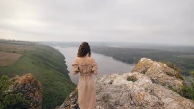 Gün doğumunda nehir manzarasına bakan kıvırcık saçlı ince bir kadının portresi. Düşünceli kız kayalık sahilde deniz manzarasının keyfini çıkarıyor. Kadın başını çeviriyor. Rahat bayan. Boş zaman konsepti