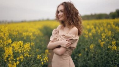 Dışarıdaki çiçek tarlasında duran gülümseyen bir kadının portresi. Kıvırcık saçlı, tatlı tatlı gülümseyen cilveli bir kız. Bir yaz günü, çiçek açan bir tarlada kendini özgür hisseden genç bir kadının yakın çekimi..