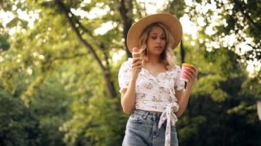 Hasır şapkalı genç bir kadın önce hangisini deneyeceğini seçemez. Dondurma mı kahve mi? Kız tatildeyken dondurma yer ve kahve içer.