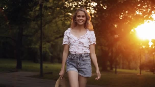 Šťastná Blondýnka Chodí Parku Usmívá Kamery Nasazuje Slamák Vesele Odchází — Stock video
