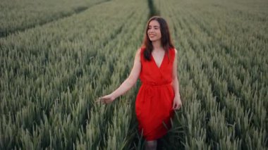 Kırmızı elbiseli genç bir esmer, yeşil buğday tarlasında yürüyor, elleriyle mısırın kulaklarına dokunuyor ve insanlık için temiz ve sürdürülebilir bir gelecek düşlüyor.