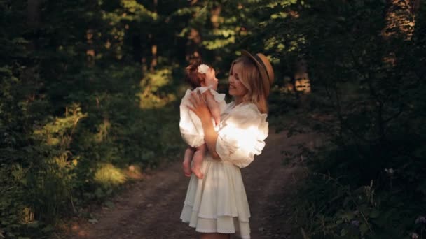 年轻的微笑的母亲在公园里散步时拥抱和亲吻她新生的小女儿 母亲和孩子在一起 — 图库视频影像
