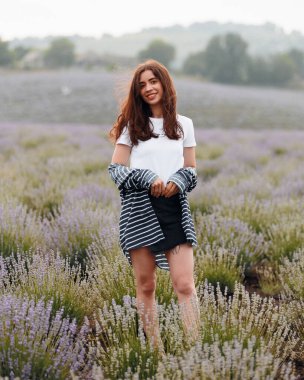 Lavanta tarlasında yürüyen uzun saçlı, gülümseyen güzel bir kadının portresi. Lavanta çiçeği tarlası. Doğada yaz tatili