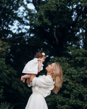 Açık havada mutlu ve uyumlu bir aile. Annem yazın çocuğu atar, güler ve doğada oynar.