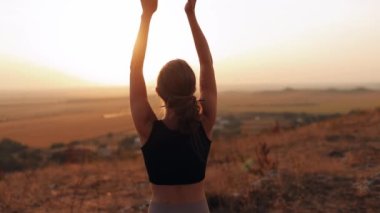 Yoga egzersizleri ve günbatımında saha manzaralı meditasyon. Beyaz tenli sporcu kadın dışarıda yoga eğitimi alıyor. Sağlıklı yaşam tarzı kavramı.