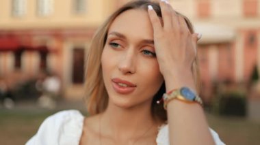 Çekici, sarışın, uzun saçlı, gülümseyen seksi kadının yüzünü kapat. Göz kamaştırıcı bir kızın portresi kameraya bakıyor ve dışarıda sıcacık gülümsüyor.