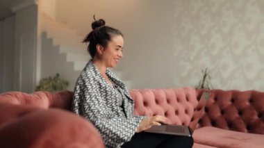 Gülümseyen genç bir kadın dizüstü bilgisayar kullanarak ekran daktilo mesajlarına bakıyor, mutlu bir bayan sohbet ediyor internette geziniyor sosyal medyada çalışıyor ya da evde online çalışıyor.