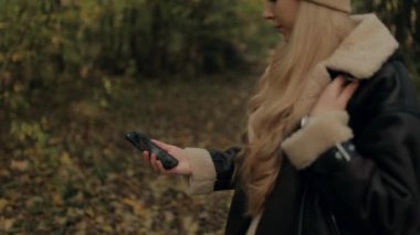 Sarışın kadın turist dijital haritaya ya da akıllı telefondan pusula bakıp yol bulmaya çalışıyor. Kafası karışık bir kadın turist gideceği yere GPS kullanarak varmak istiyor.