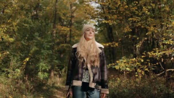 背着背包的女游客在秋天的森林里散步 她一个人在野外的人行道上散步 在林地行走 旅游概念 — 图库视频影像