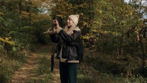 秋天森林里的女游客用智能手机拍照 在秋天的森林里散步的女人 享受大自然 — 图库视频影像