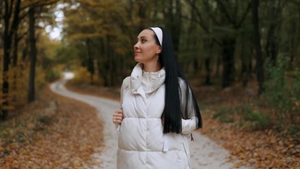一个年轻的女人走过一个天然的森林 一个女人独自远足秋天公园里人声鼎沸 积极的生活方式 森林里的人一个游客在秋天的森林公园散步 — 图库视频影像