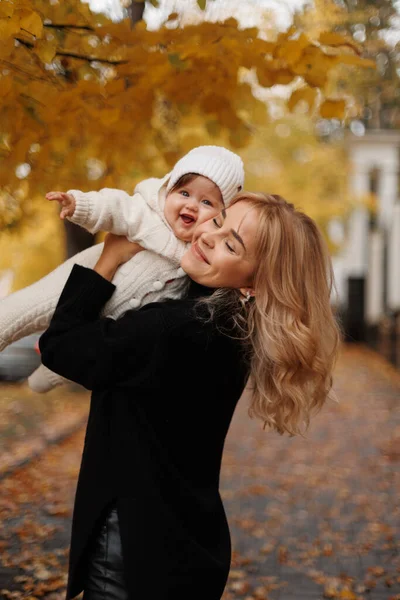 Sonbahar Parkı 'nın arka planında poz veren küçük kızı tutan mutlu kadın. Aile yaşam tarzı konsepti. Annelik. Sonbahar sezonu. Kız ve anne birlikte portre
