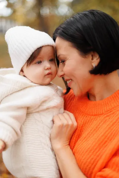 Güneşli bir günde, bir sonbahar parkında kollarında bir anne ve kızının portresi. Torunum ve büyükannem.