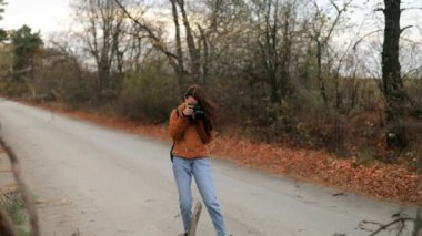 Kameralı genç bir kadın gezgin, kuşları, hayvanları, manzarayı vuruyor. Sırt çantalı bir turist kadın sonbaharda tek başına seyahat ederken kameraya fotoğraf çekiyor.