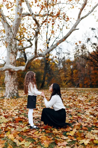 Mutlu aile: anne ve çocuk küçük kız sonbahar yürüyüşünde kucaklaşır, doğada gezer, eğlenir ve gülümserler, birlikte yürüyüş yaparlar, anne ve kız birbirlerini severler.
