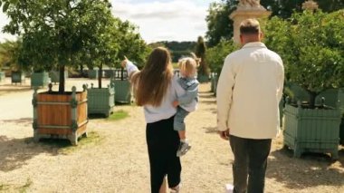 Versailles narenciye bahçesinde yürüyüş yapan mutlu bir aile. Anne, baba ve kızı birlikte seyahat ediyorlar. Arka görünüm