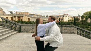 Bir adam ve bir kadın, birbirine aşık bir çift birbirlerine doğru koşuyorlar, bir adam Versailles bahçesinin ve şatosunun arka planında kadınını çeviriyor.