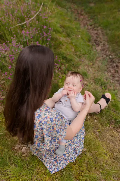 Mutlu kadın ve çocuk baharda ya da yaz bahçesinde. Anne ve oğul oynuyorlar, sarılıyorlar ve gülümsüyorlar. Aile tatili ve birliktelik