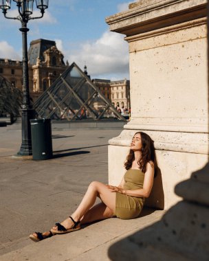 Yazın Louvre 'da, güneşli bir günde Paris' te yürüyen, antik şehrin güzel mimarisi ve atmosferinin tadını çıkaran çekici, genç bir kadın turistin yakın portresi.