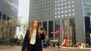 Genç, çekici, uzun saçlı kadın bir toplantıya ya da işe gitmek için acele ediyor, akıllı telefonundaki saate bakıyor ve Paris 'in iş merkezindeki cadde boyunca koşuyor.