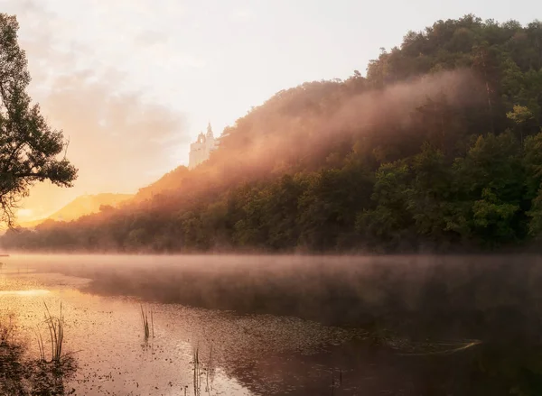Beautiful landscape with morning fog at sunrise. Temple on chalk cliffs at dawn, over the river. Ukrainian landscape. River Siverskiy Donets, Sviatohirsk