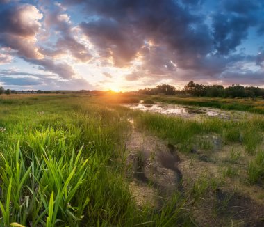 Scenic sunset over a swampy stream, marsh. Dramatic clouds, soft light. Camping, hiking, outdoor lifestyle concept.