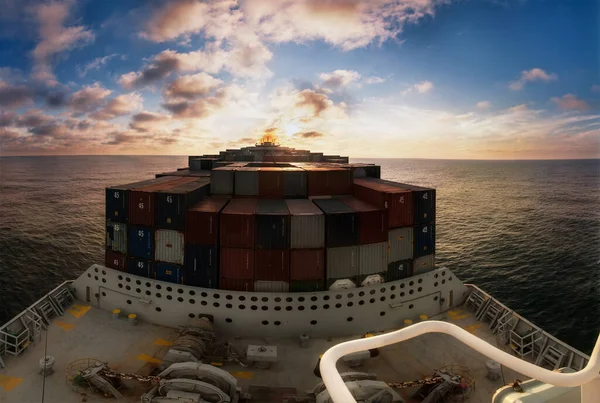 Large container ship sailing through the sea or ocean. View from the forward mast on the loaded deck and navigational bridge.