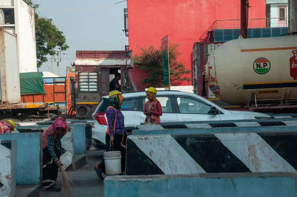 Gandhidham, Gujarat, India - 12 02 2022: Indian municipal worker with weared helmets sweep the road with a broom.