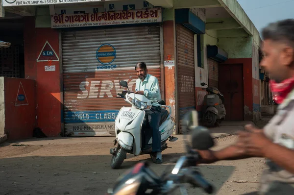 Gandhidham, Gujarat, India - 12 02 2022: A man without helmet parked his scooter along city street.