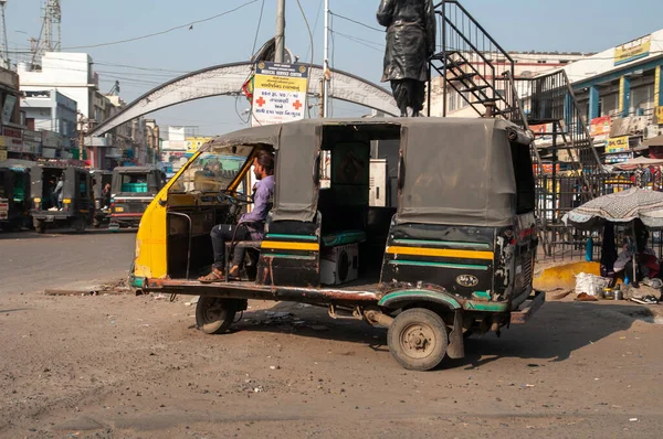 Mundra, Gujarat, India - 12 02 2022: Tuk-tuk at the parking lot waiting for passengers. The driver sits in the driver's seat.