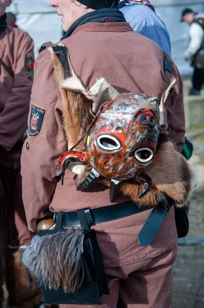 Hohenstadt - February 17, 2023: Participant of a parade with mask at the traditional carnival parade in Hohenstadt, Germany. The mask has been taken off and is hanging on the back.