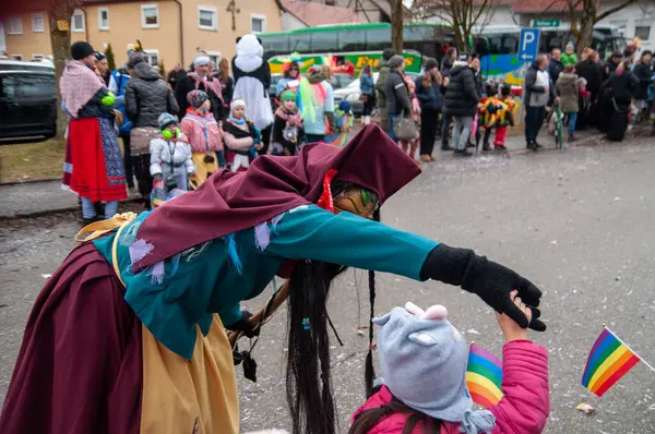 Hohenstadt - February 17, 2023: Participant of a parade in witch mask and costume at the traditional carnival parade in Hohenstadt, Germany. Dancing with the kids