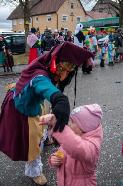 Hohenstadt - February 17, 2023: Participant of a parade in witch mask and costume at the traditional carnival parade in Hohenstadt, Germany. Dancing with the kids