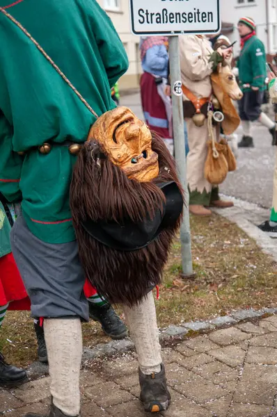 Hohenstadt - February 17, 2023: Participant of a parade with mask at the traditional carnival parade in Hohenstadt, Germany. The mask has been taken off and is hanging.