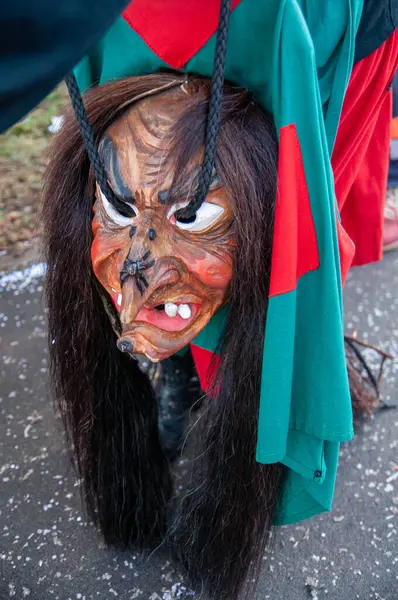 Hohenstadt - February 17, 2023: Participant of a parade with mask at the traditional carnival parade in Hohenstadt, Germany. The mask has been taken off and is hanging.