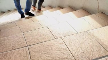 person walking up the stairs. front view of man wearing trousers and shoes walking up stairs outdoors in office.