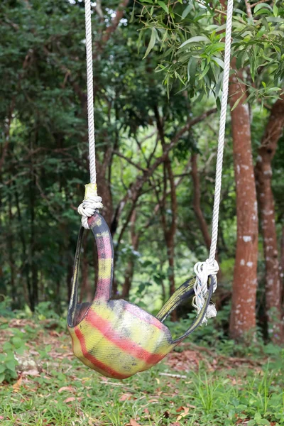swing in the forest. tire swing. made from used car tires that are painted. children\'s toys, in the garden. recycled material.