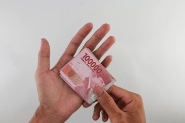 Indonesian rupiah currency. close up One hundred thousand rupiah. 100000 rupiahs. with the concept of being held by hand. receive financial assistance. white background. isolated, studio photography.