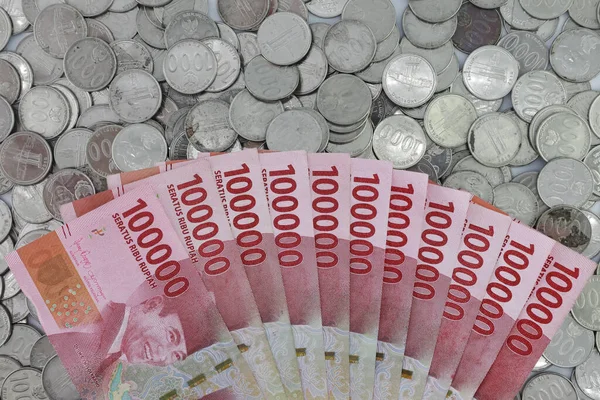 Indonesian rupiah currency. One hundred thousand rupiah banknotes, one thousand rupiah coins. 100000 rupiahs and 1000 rupiahs. with full framing concept isolated white background.
