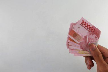 Indonesian rupiah currency. close up One hundred thousand rupiah. 100000 rupiahs. with the concept of being held by hand. receive financial assistance. white background. isolated, studio photography.