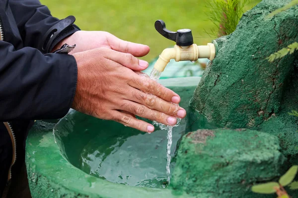 the activity of washing both hands in the sink, running water in the faucet. healthy lifestyles. maintain cleanliness. outdoor sink.