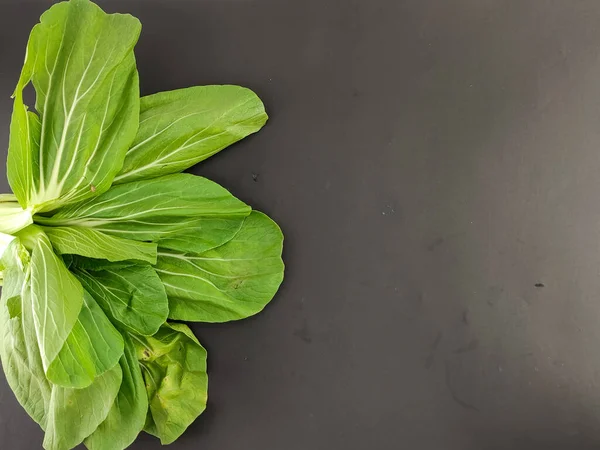 Fresh green mustard, vegetables nourish the body. caisim, Brassica Rapa Parachinensis group. isolated black background, photography studio, negative space. seen from above.