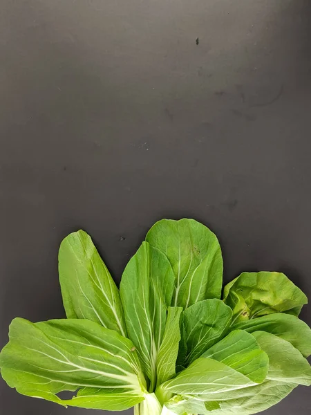 Fresh green mustard, vegetables nourish the body. caisim, Brassica Rapa Parachinensis group. isolated black background, photography studio, negative space. seen from above.