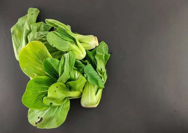 Fresh green mustard, vegetables nourish the body. caisim, Brassica Rapa Parachinensis group. isolated black background, photography studio, negative space. seen from above.