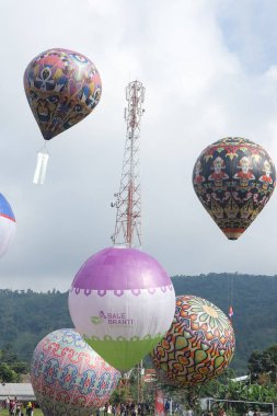 Karanganyar, Endonezya - 20 Kasım 2022. Sıcak Hava Balon Festivali. Renkli dev balonlar. Halk festivali coşkuyla kutluyor. Kalabalık. Tepe manzaralı bir futbol sahasında.