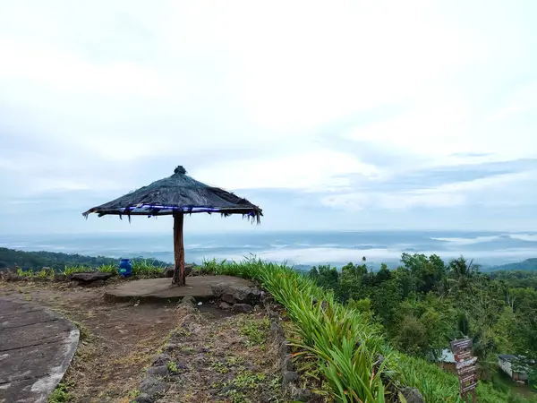 hut or shelter on a hill. wooden umbrella. against a cloudy blue sky background.