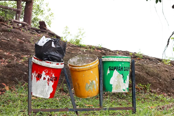 throwing trash in the bins according to color. green for organic waste, yellow for inorganic waste and red for B3 waste or toxic and hazardous materials.